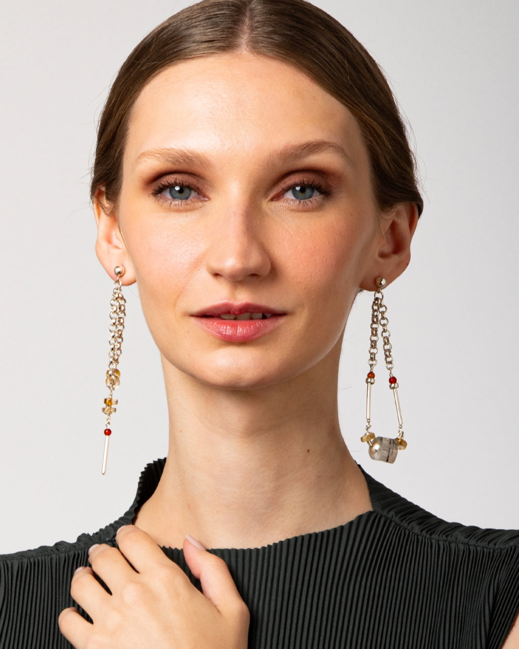 Modelo usando brincos minimalistas em prata 925 com calcitas laranja naturais da linha ESSENTIAL da A'IUNE.