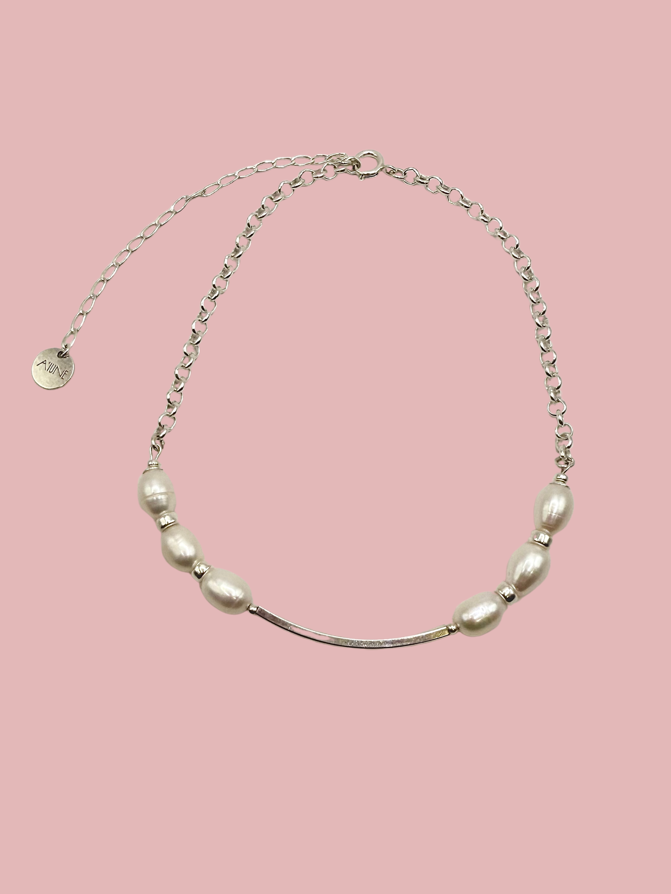 Colar Essential em prata 925 com pérolas naturais de água doce sobre fundo rosa, joia artesanal da A'IUNE.
