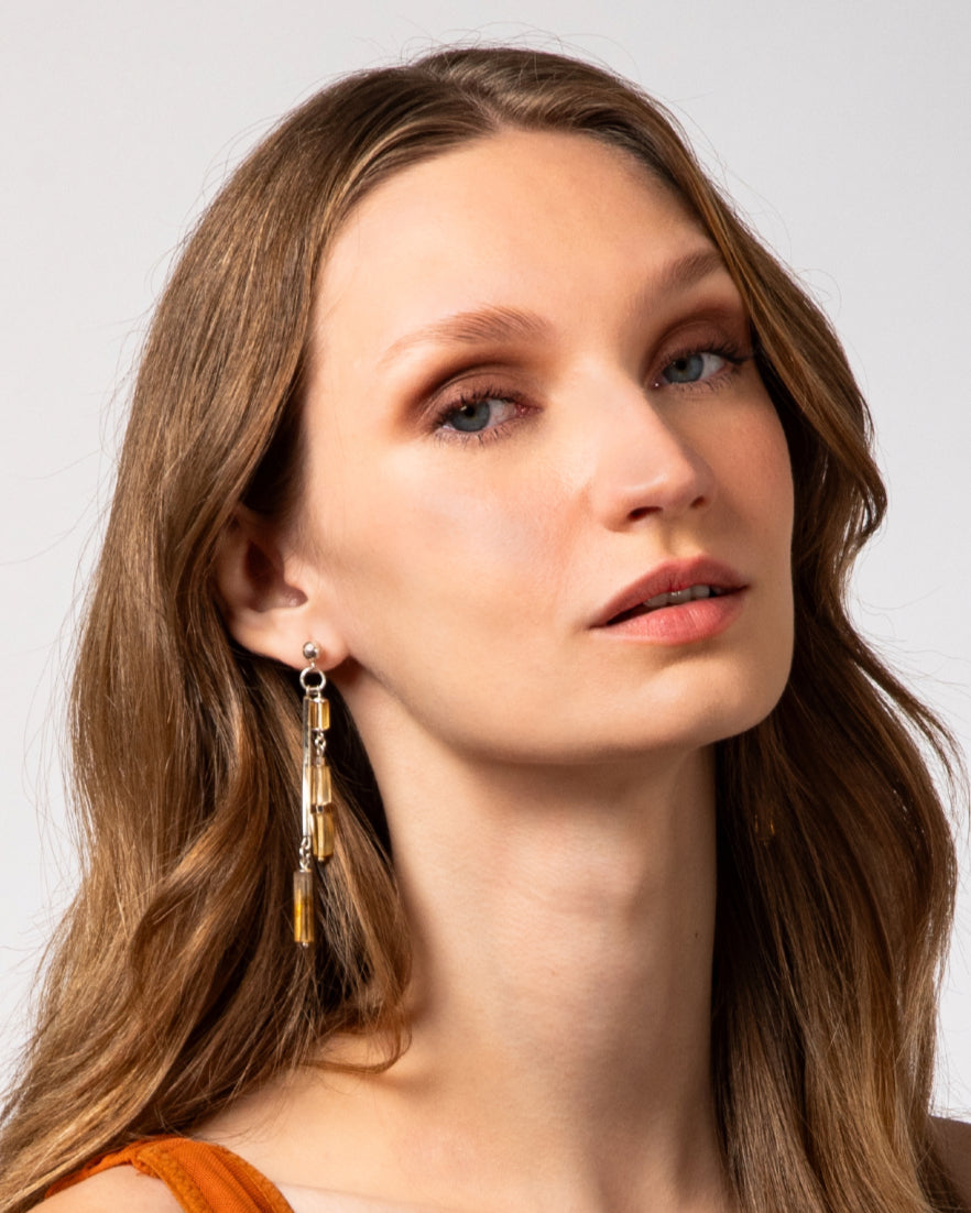 Modelo usando brincos assimétricos em prata 925 com citrinos naturais da linha COUTURE da A'IUNE.