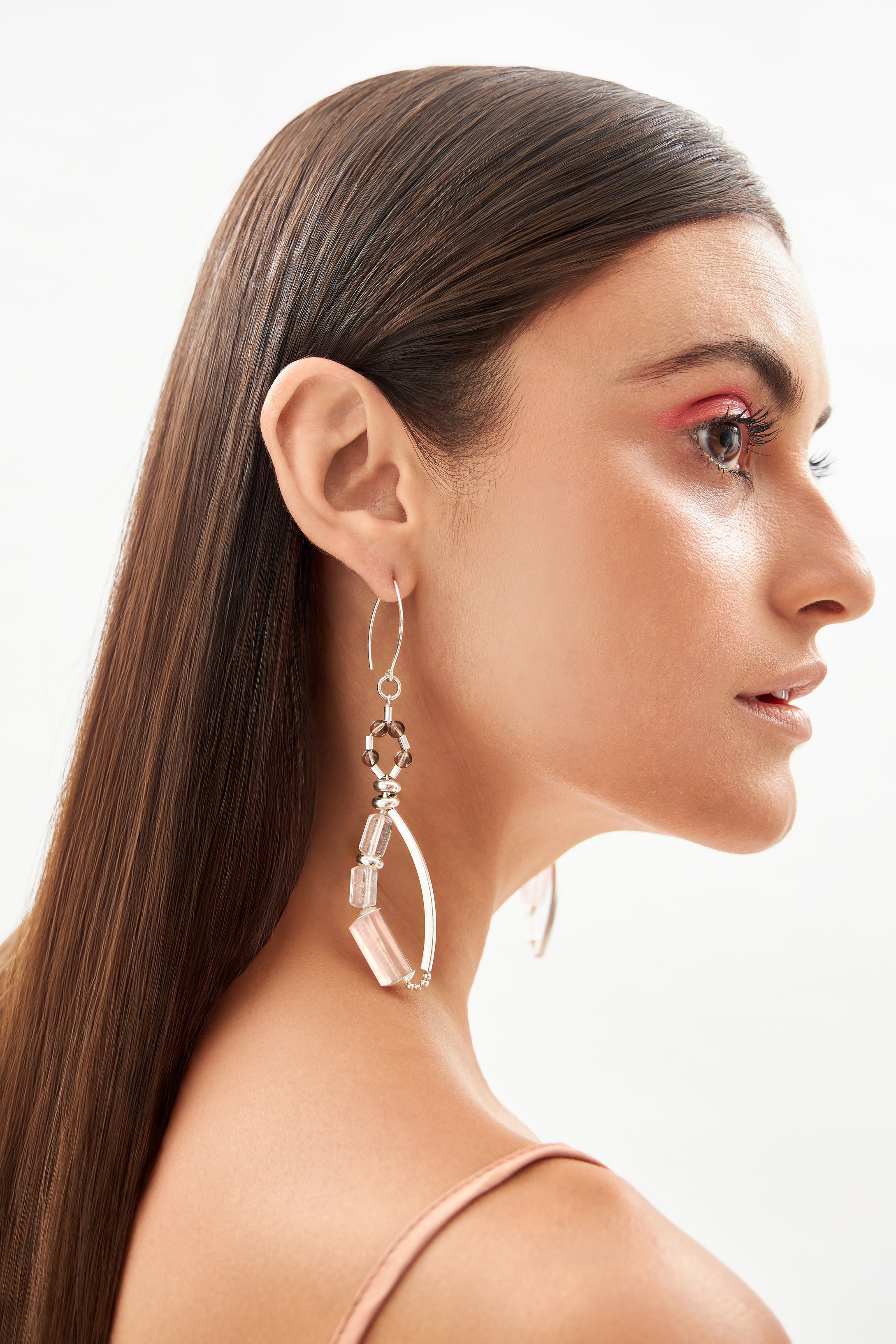 Modelo em perfil usando brincos alongados em prata 925 com quartzo rosa, âmbar e cristais naturais.