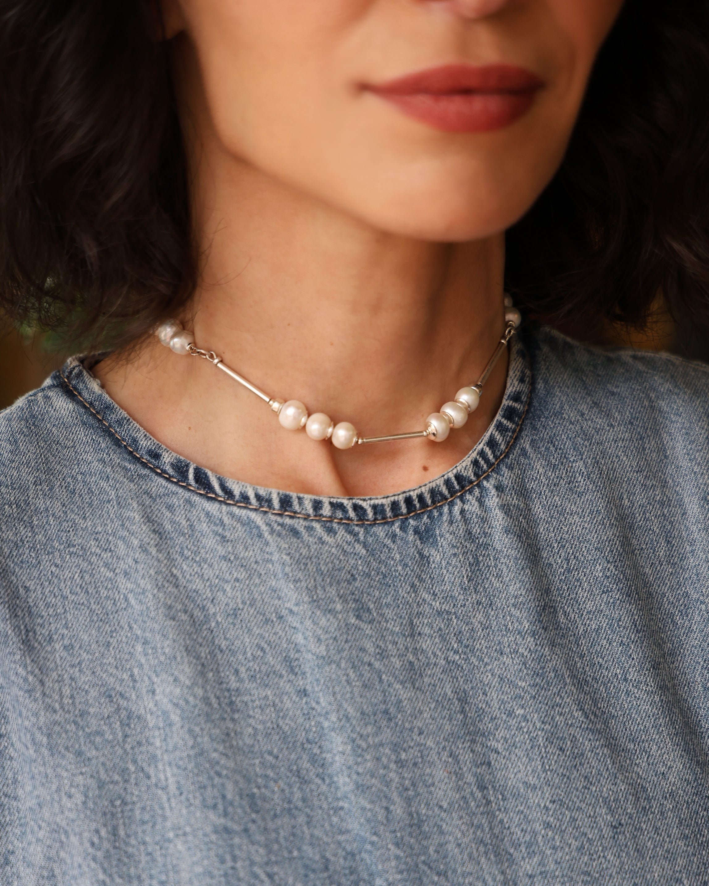 Close do colar em prata 925 com pérolas naturais de água doce usado no colo, joia delicada da linha COUTURE.