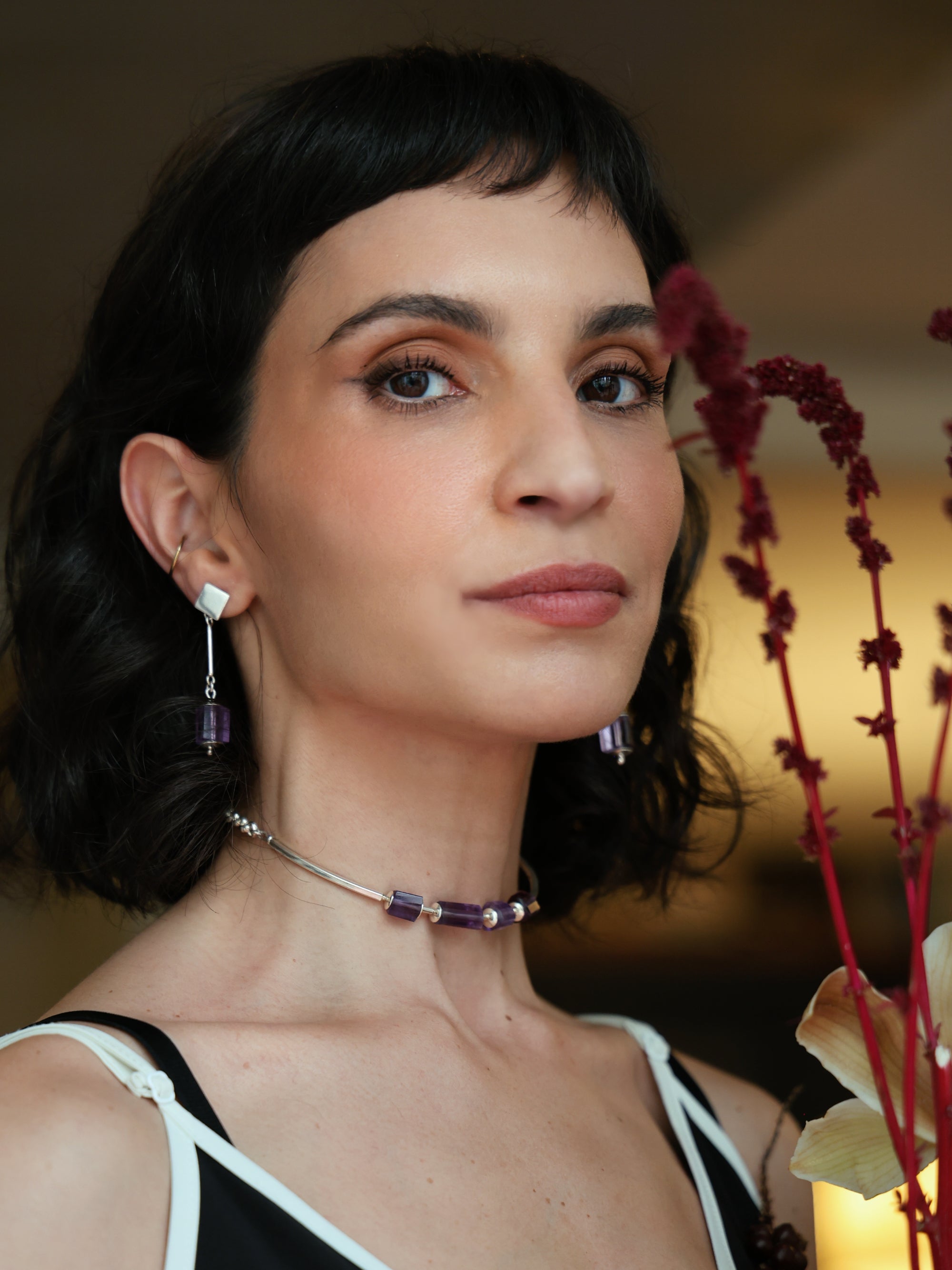 Modelo usando colar Essential A'IUNE com ametistas naturais em composição editorial com flores.